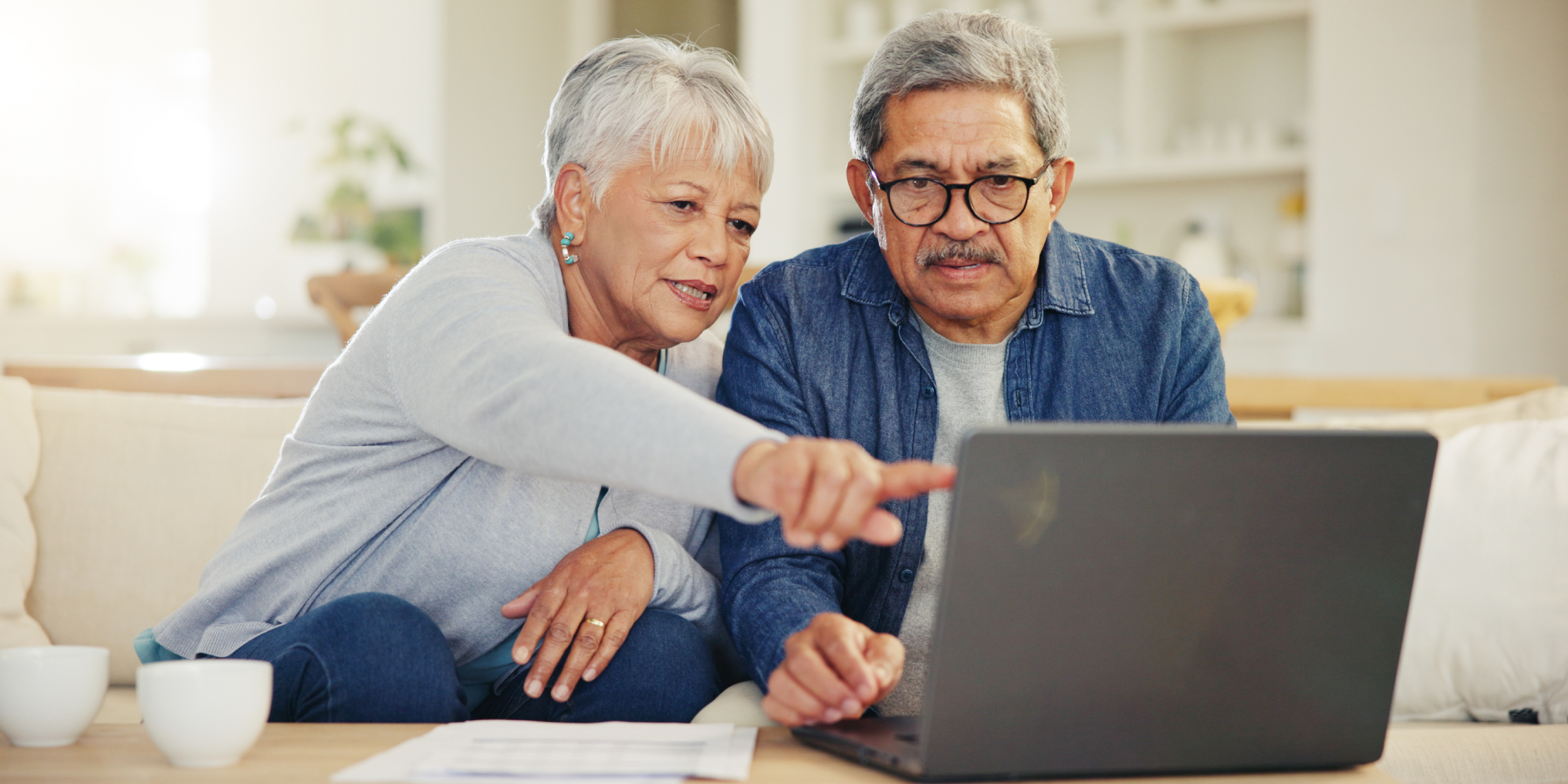 Elder couple sitting on couch looking at laptop together